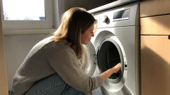 Žena kontroluje práčku v kuchyni pri dennom svetle