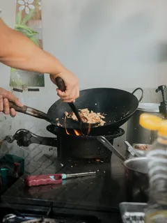 Osoba varí thajské jedlo v woku na sporáku
