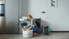 Žena vkladá prádlo do práčky v práčovni