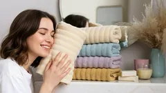 Žena si užíva hebkosť farebných uterákov v kúpeľni, spokojnosť a pohodlie domova.