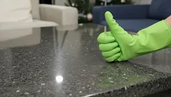 Čistý povrch stola, zelená rukavica ukazuje palec hore, upratovanie domácnosti.
