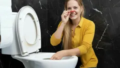 Žena čistí toaletu a drží si nos pred nepríjemným zápachom, čistenie WC doma.