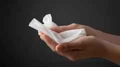 Ruky držiace vlhčený obrúsok na tmavom pozadí, hygienické potreby, starostlivosť