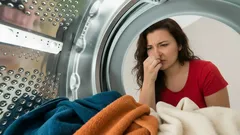 Žena si drží nos pri zapáchajúcej bielizni v práčke