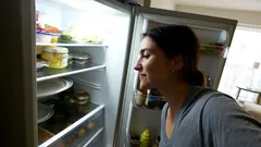 Žena hľadí do otvorenej chladničky v domácej kuchyni