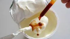 Prírodný jogurt s pridanou vanilkovou esenciou v plastovom kelímku na lyžičke.